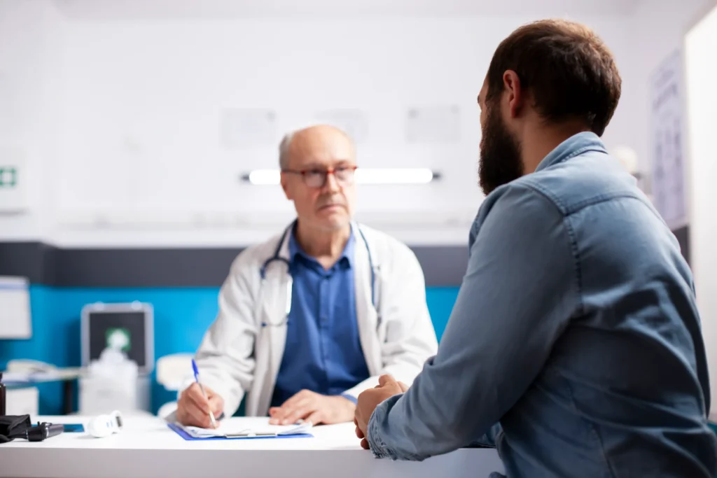 Male patient discussing persistent erectile dysfunction symptoms with a doctor during a consultation.