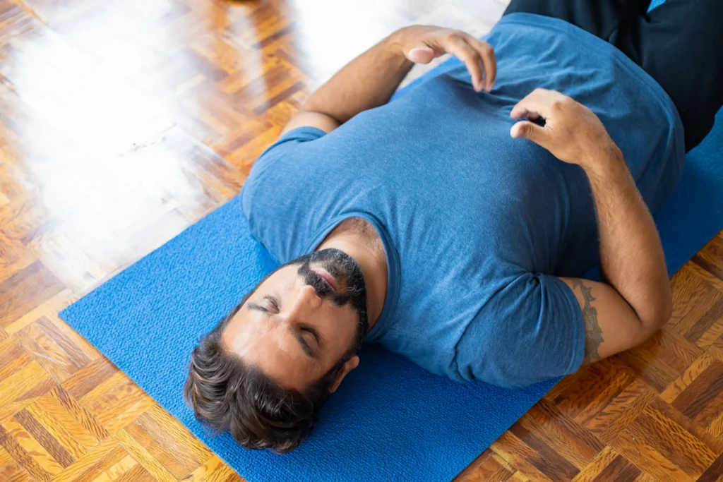 Man lying on an exercise mat during a relaxation and controlled breathing exercise.