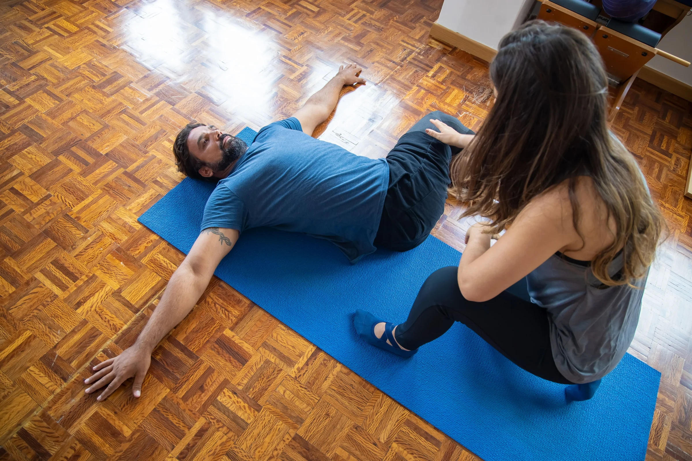 Male patient completing a guided floor exercise with a healthcare professional.