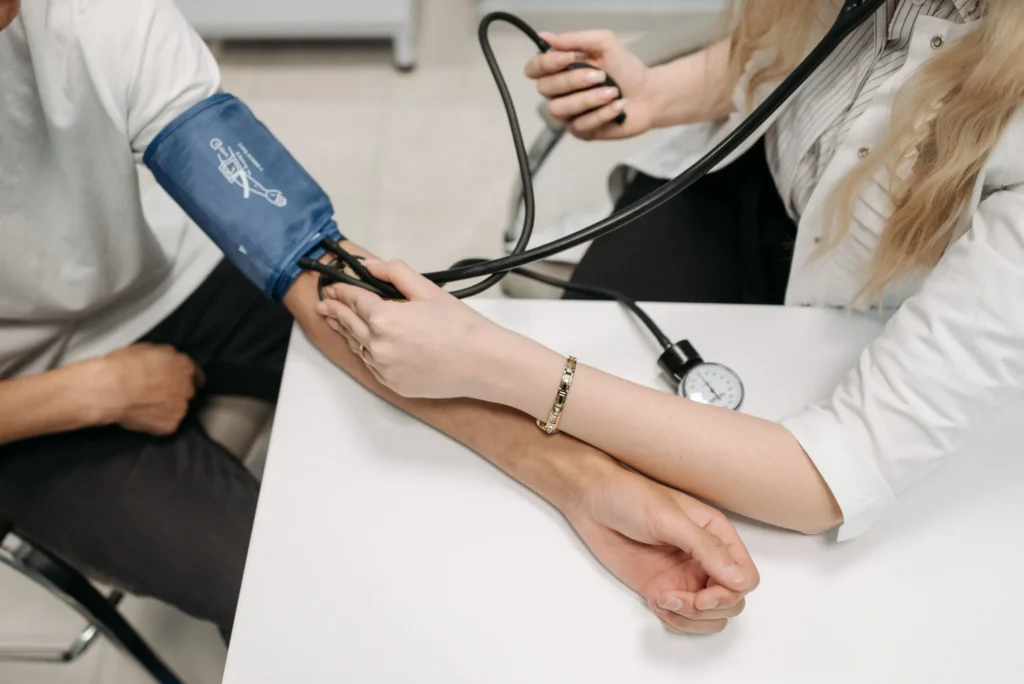 Healthcare professional checking a man's blood pressure during an assessment.
