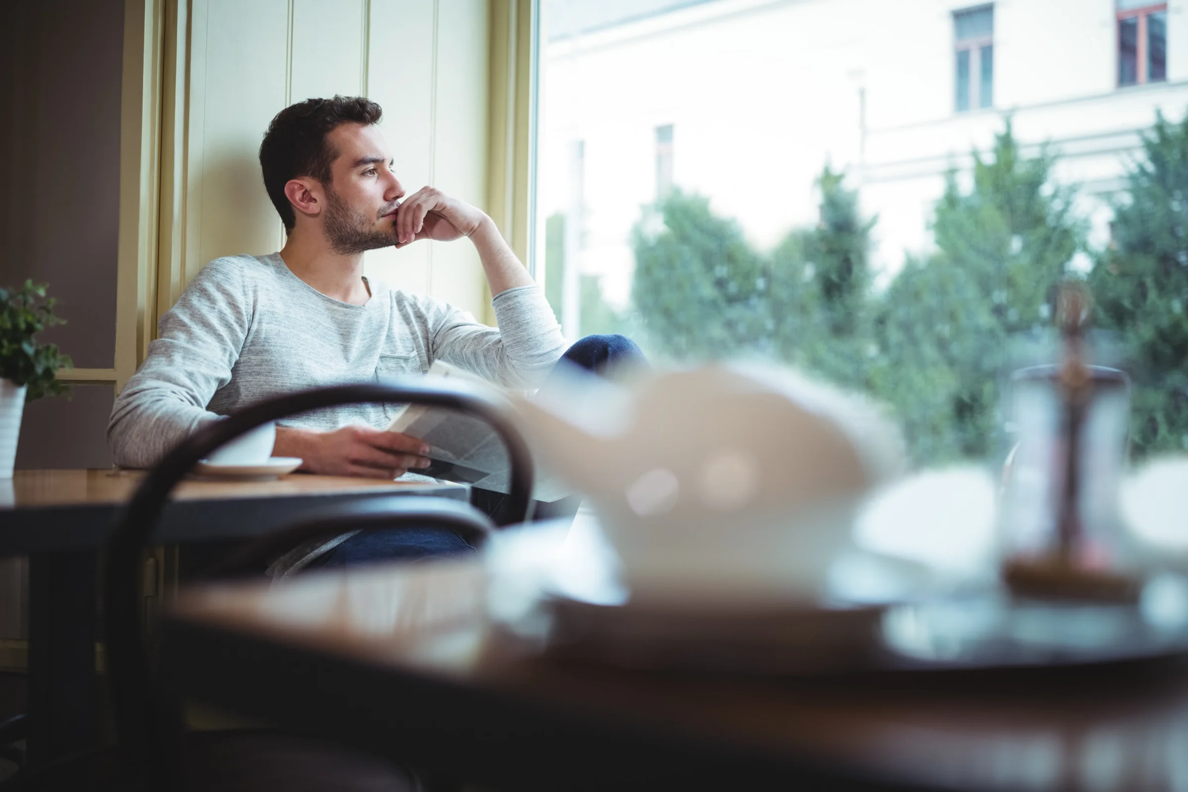 Man sitting thoughtfully by a window while considering his health.